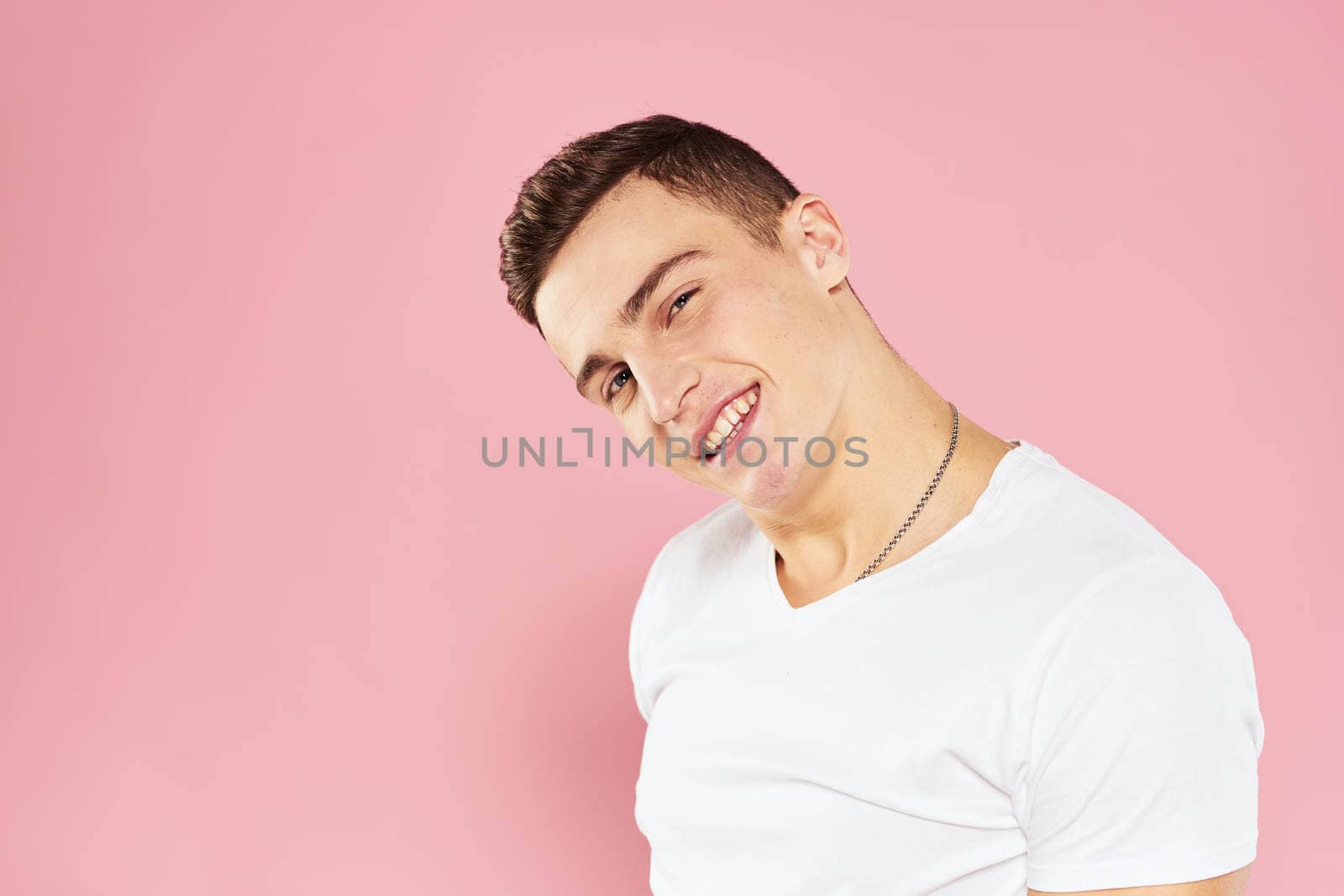 Cheerful handsome man in white t-shirt emotions pink isolated background. High quality photo