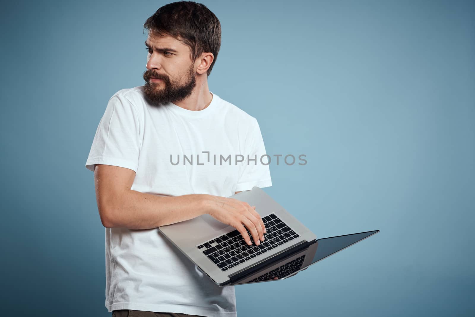 Emotional man with laptop in hands on blue background monitor keyboard internet model cropped view. High quality photo