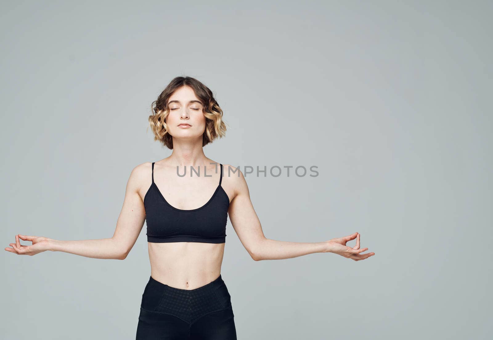 Woman in sportswear gestures with her hands on a gray background Copy Space. High quality photo