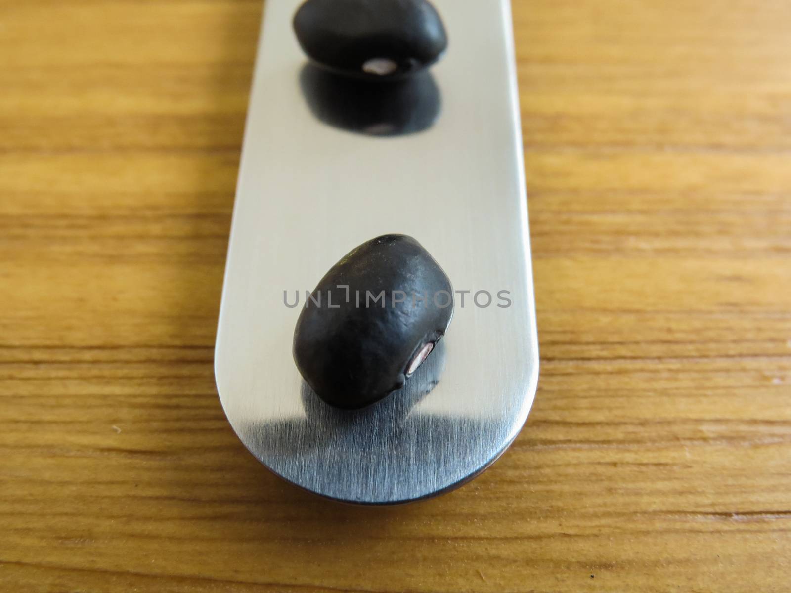 Spatula with two black beans on wooden table. by silviopl