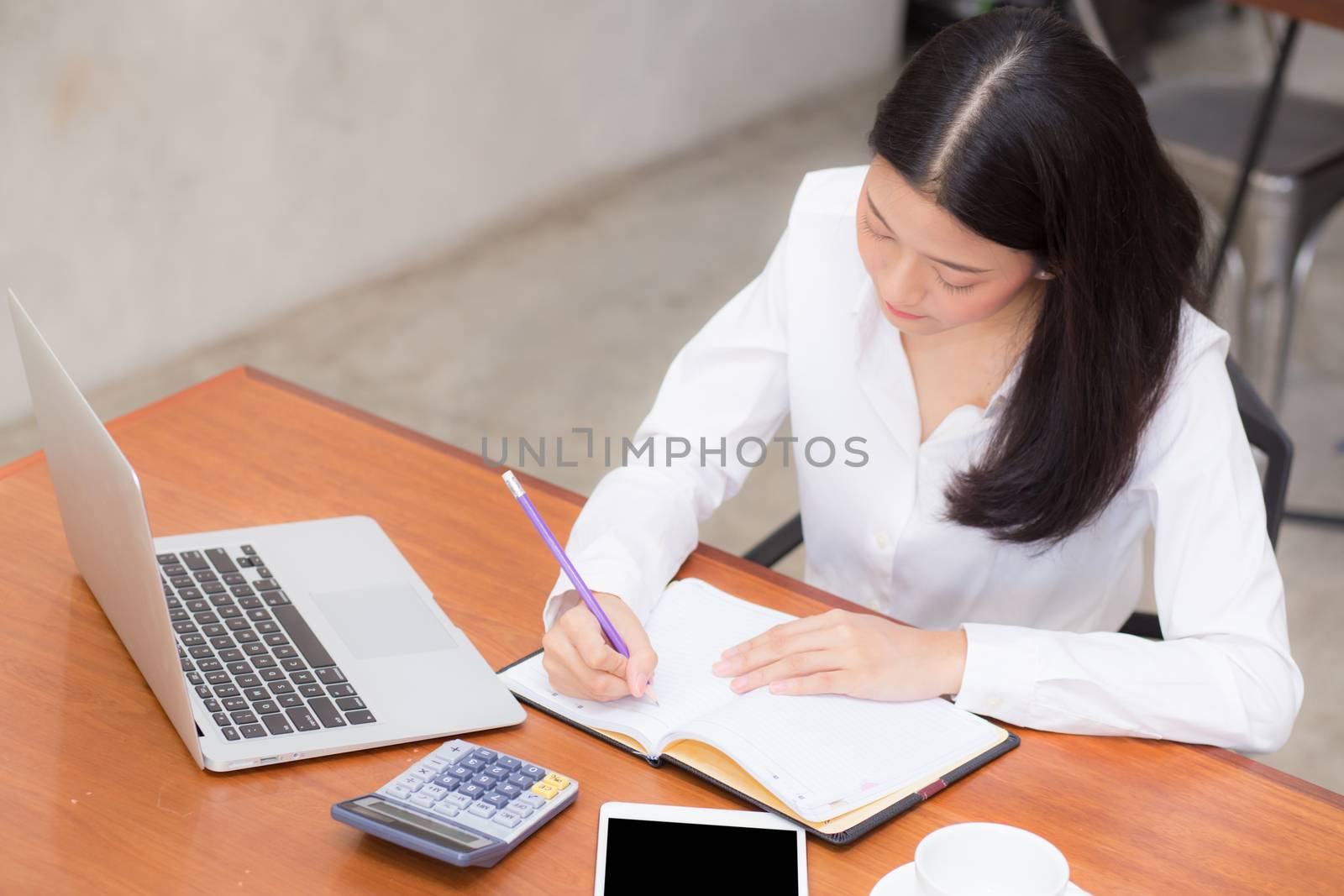 Business asian woman writing on notebook on table with laptop, girl work at coffee shop, freelance business concept.