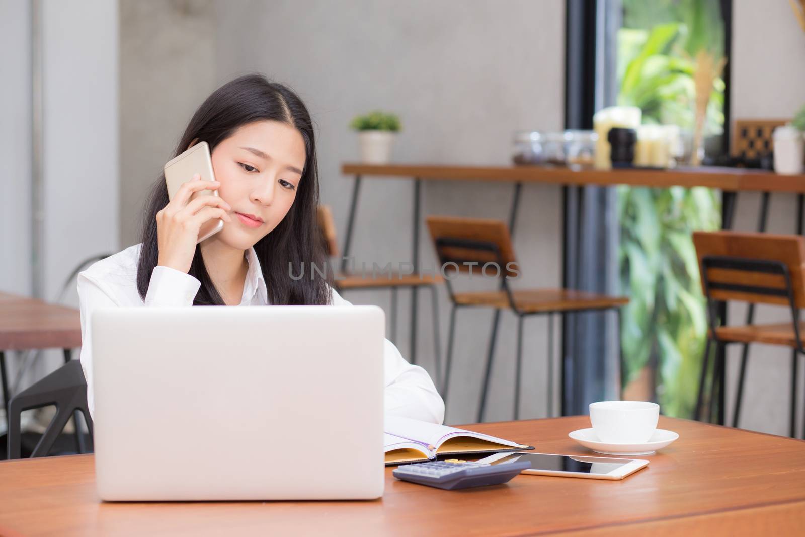 Beautiful asian young businesswoman excited and glad of success with laptop, girl taking mobile phone and working coffee shop on cement background, career freelance business concept.