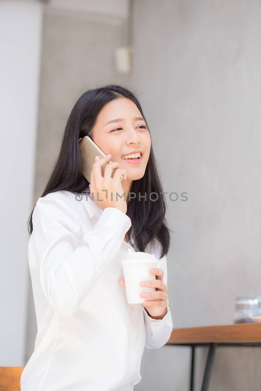 Beautiful young asian woman talking phone and smile in the coffee shop, businesswoman sitting in cafe free time, freelancer female calling telephone, communication concept.