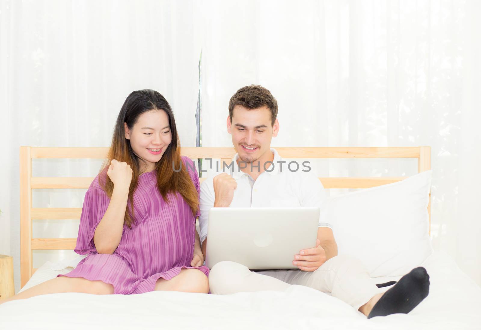 Beautiful pregnant family with laptop computer on bedroom, husba by nnudoo