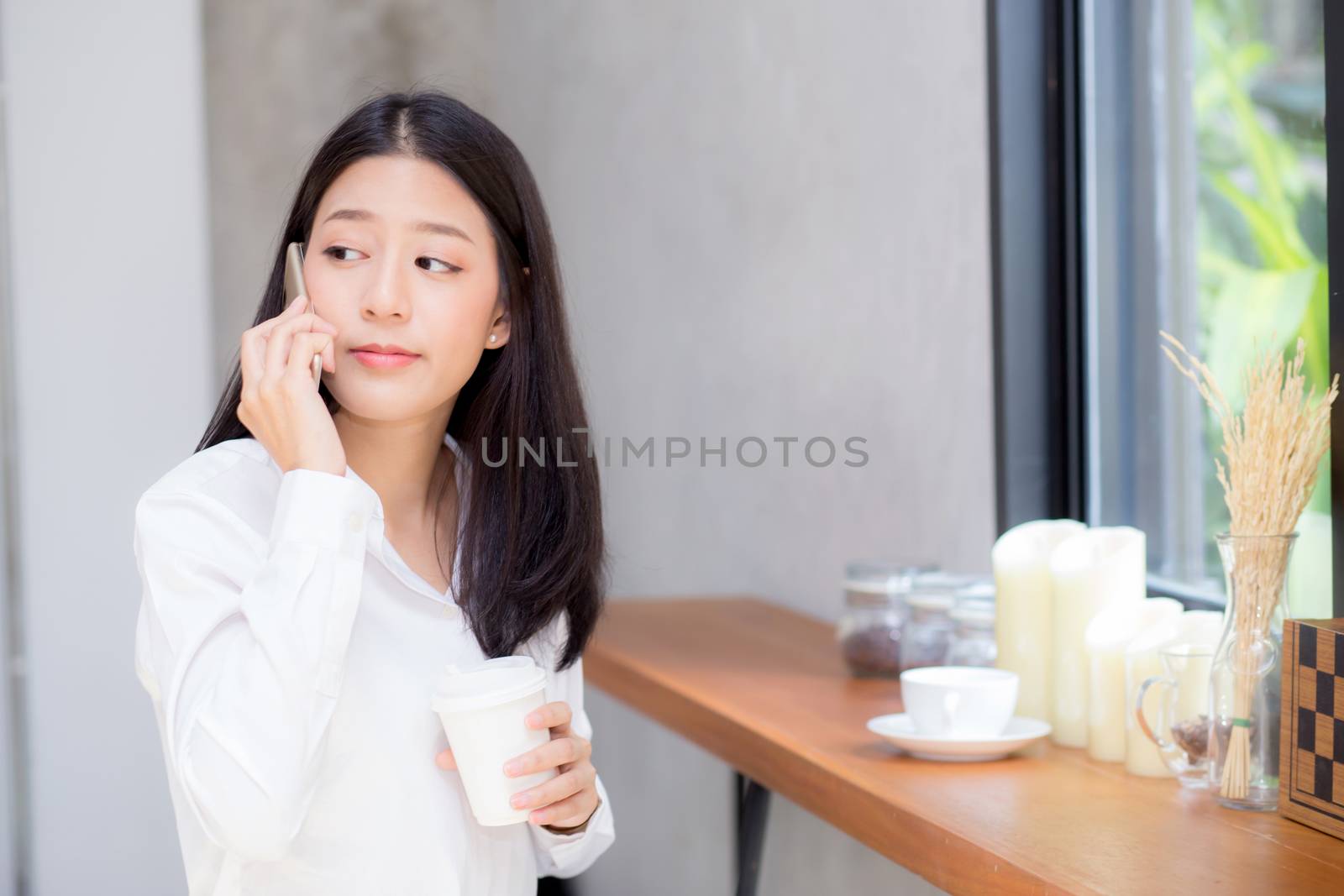 Beautiful young asian woman talking phone and smile in the coffee shop, businesswoman sitting in cafe free time, freelancer female calling telephone, communication concept.