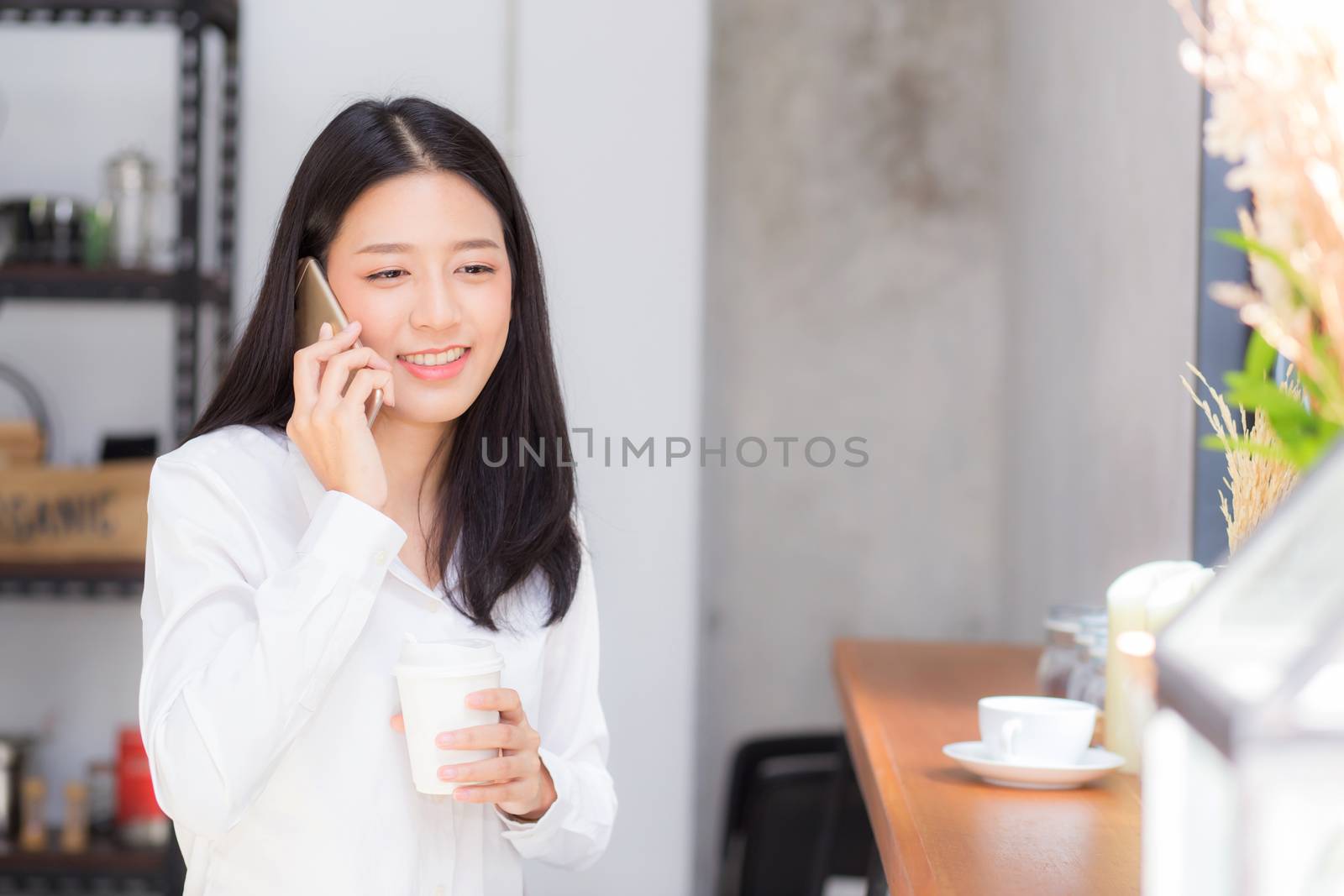 Beautiful young asian woman talking phone and smile in the coffee shop, businesswoman sitting in cafe free time, freelancer female calling telephone, communication concept.