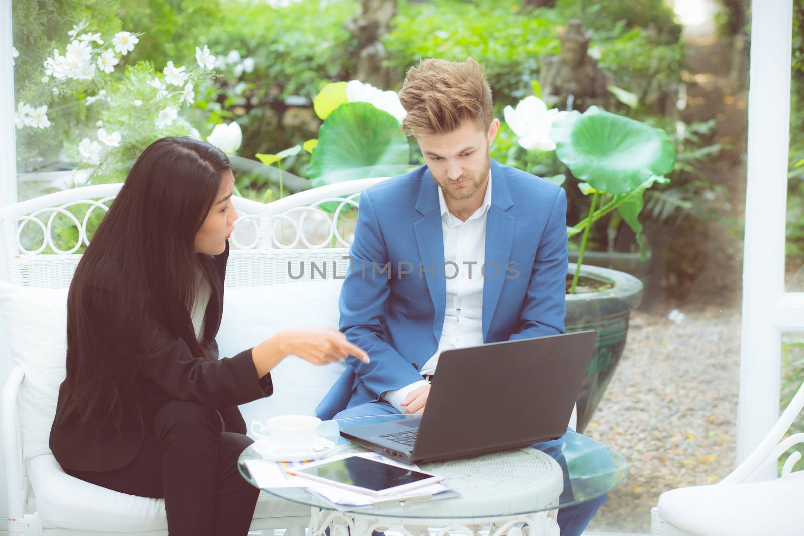 technology and office concept - two business man and woman with laptop - tablet pc computer and papers having discussion in office.