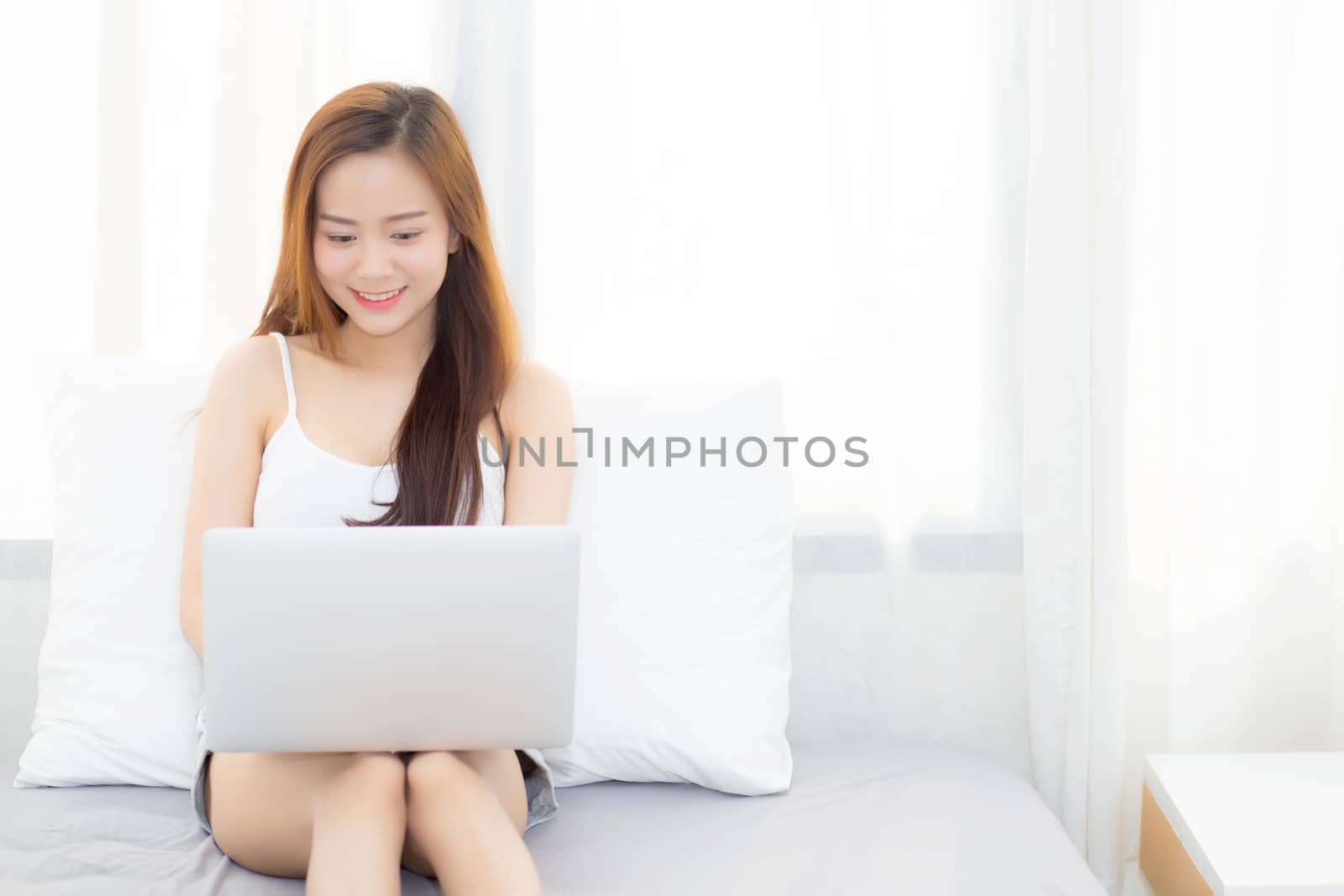 Beautiful young asian woman using laptop for leisure on bedroom, girl working online with notebook freelance, business concept.