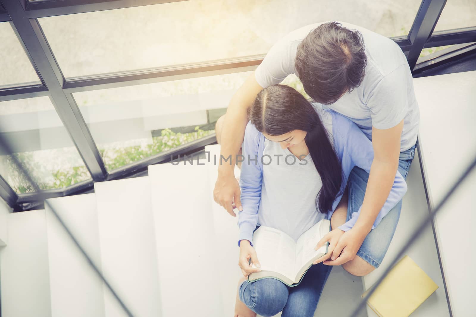 Couple asian handsome man and beautiful woman reading book and smile at home, boyfriend and girlfriend with activities together for leisure, education concept, top view.