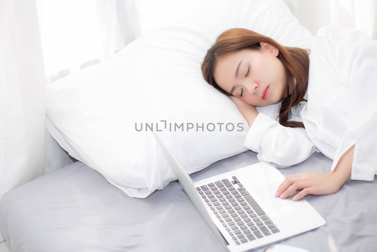 Beautiful young asian woman with laptop lying down in bedroom, girl tired sleep with computer notebook, resting and healthcare concept. 