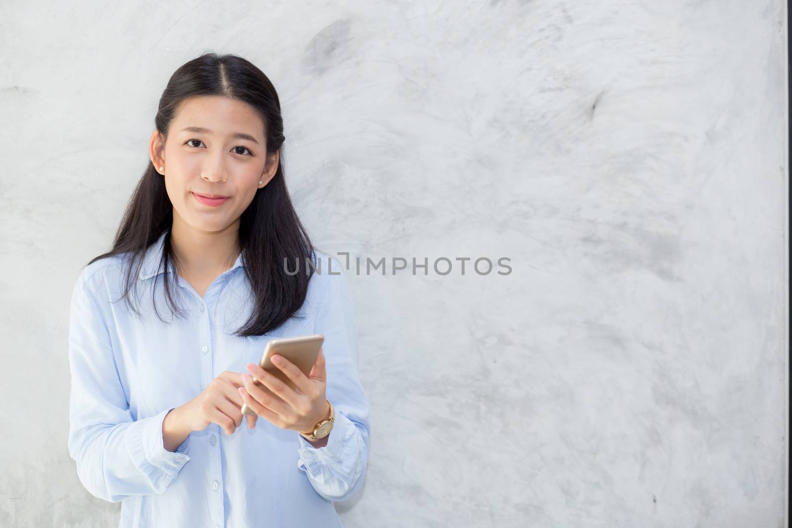 Beautiful young asian woman talking phone and smile standing on cement background, freelancer female calling telephone, communication concept.