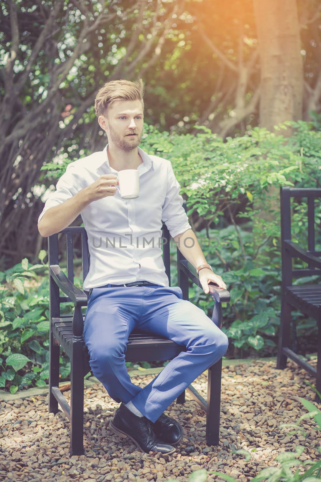 Portrait business young handsome man drink cup of coffee sitting in the park, relax and leisure concept.