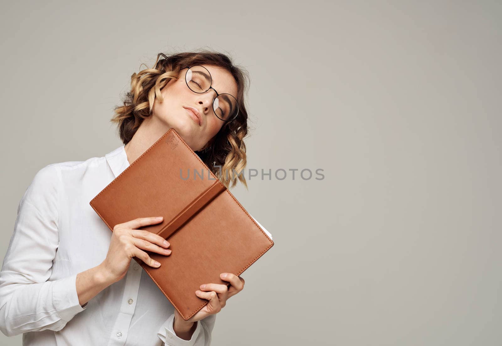 Woman with brown notepad on a gray background and glasses on her face. High quality photo