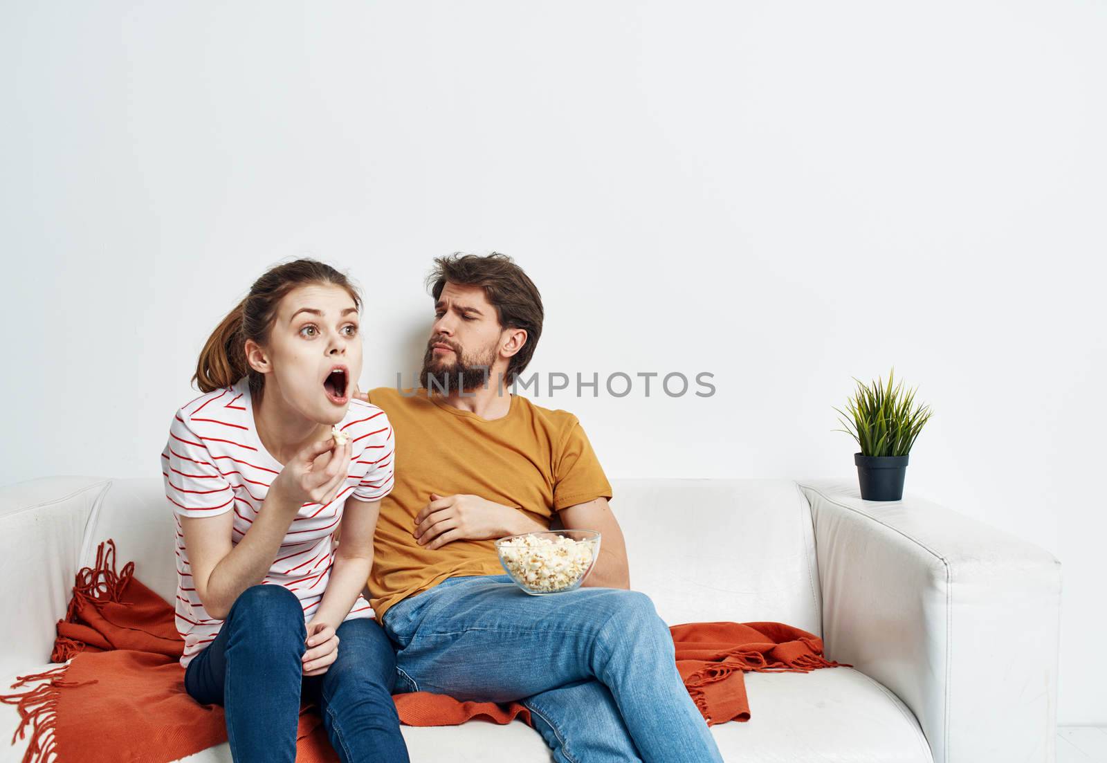 man and woman on sofa orange plaid bright room flower in a pot. High quality photo