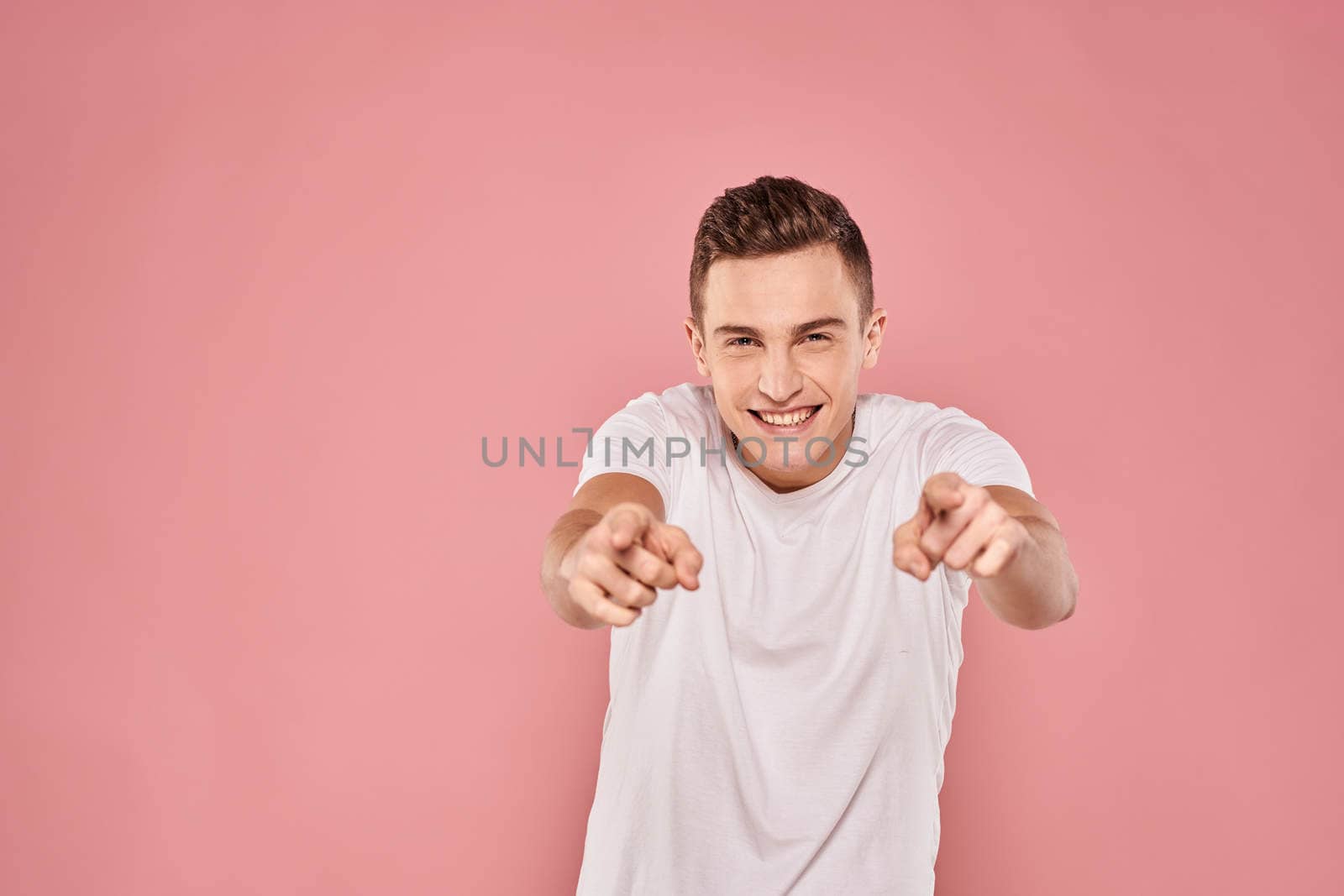 Emotional man gesturing with his hands white t-shirt pink isolated background by SHOTPRIME