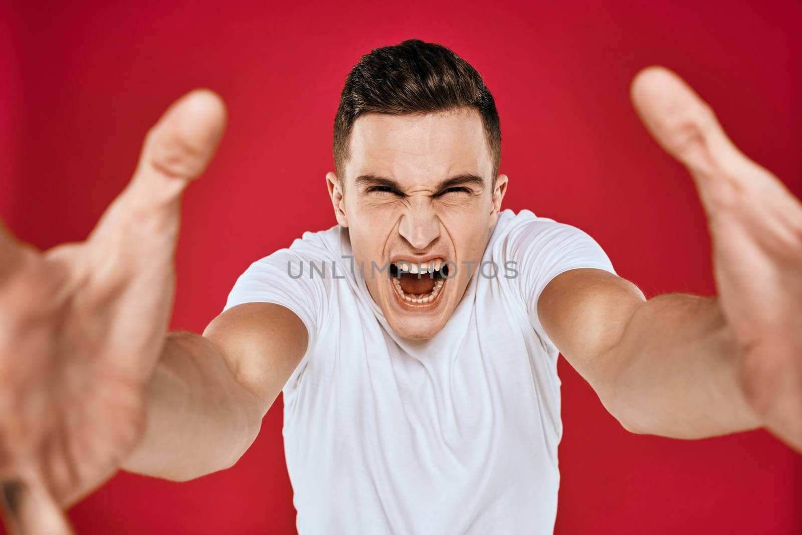 Emotional man white t-shirt displeased facial expression red isolated background cropped view. High quality photo