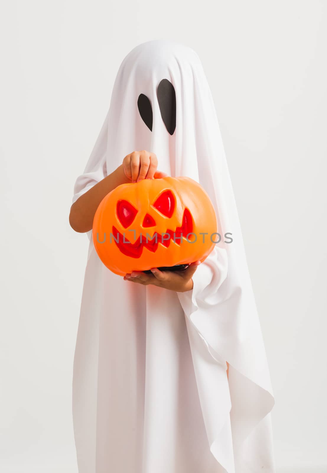 Funny Halloween Kid Concept, little cute child with white dressed costume halloween ghost scary he holding orange pumpkin ghost on hand, studio shot isolated on white background