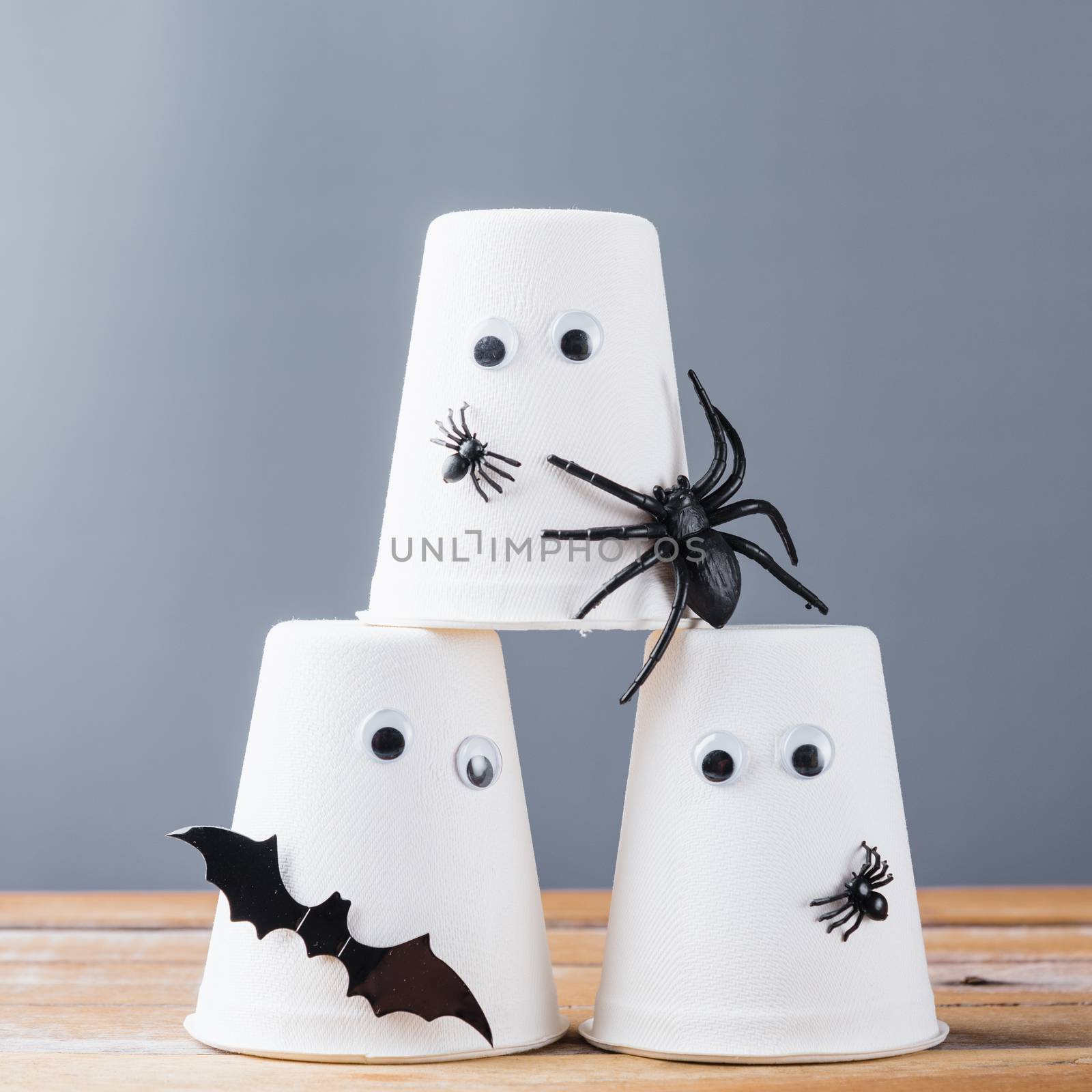Funny crafts Halloween day decoration party, closeup paper cup ghost, spider and bats on wooden wall gray background and copy space, studio shot isolated, Happy holiday concept