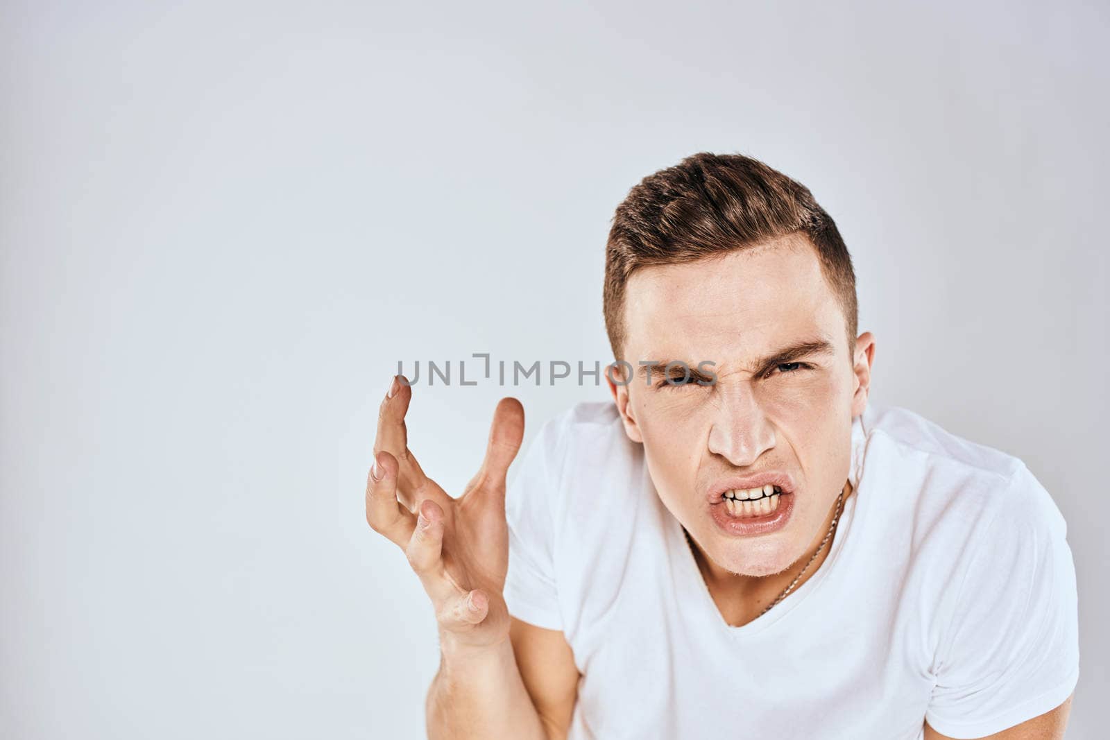 emotional man gesturing with his hands displeased facial expression white t-shirt cropped. High quality photo