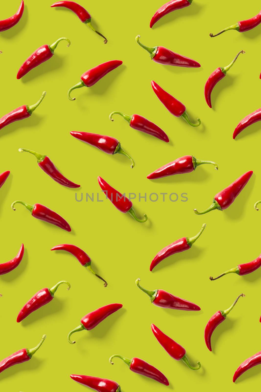 Creative background made of red chili or chilli on green backdrop. Minimal food backgroud. Red hot chilli peppers background, not pattern