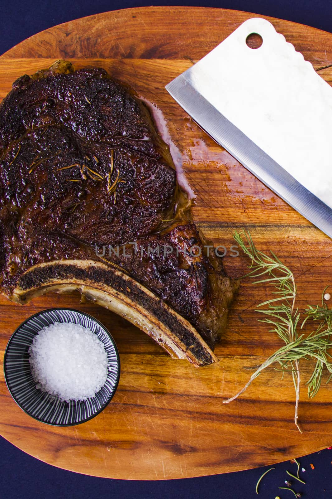 Beef steak on the wooden board, salt, pepper and rosemary.