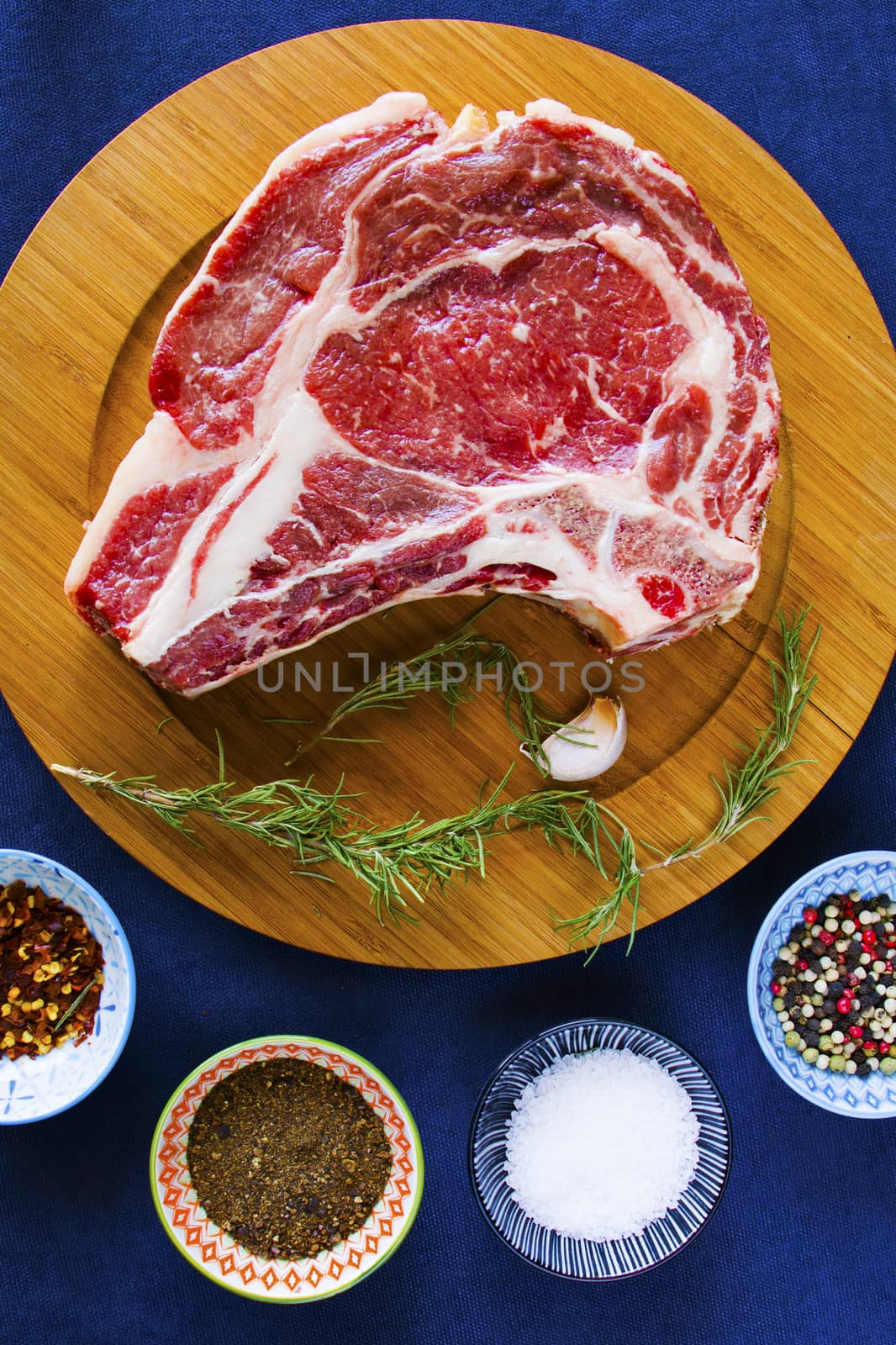 Raw beef meat on the table, spices and Rosemary, Rib eye steak ingredients. Pepper and coarse salt