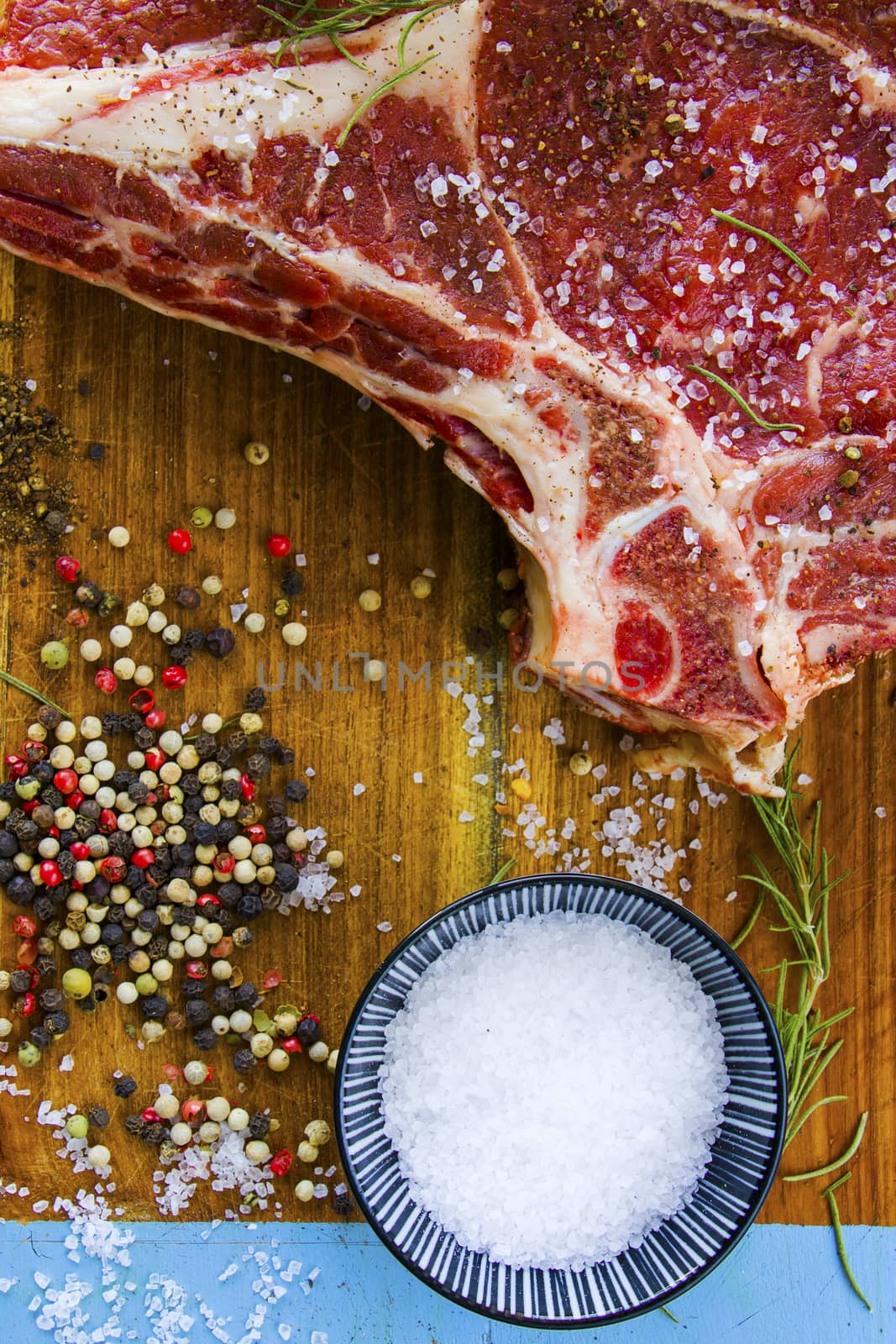 Raw beef meat on the table, spices and Rosemary, Rib eye steak ingredients. Pepper and coarse salt