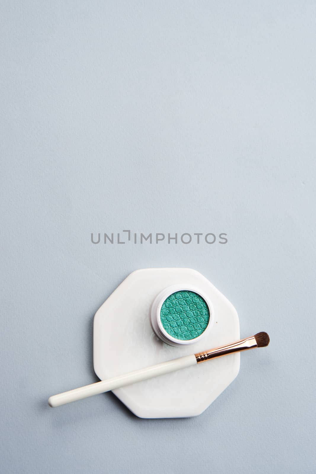 Green eyeshadow and makeup brush on white stand isolated background by SHOTPRIME