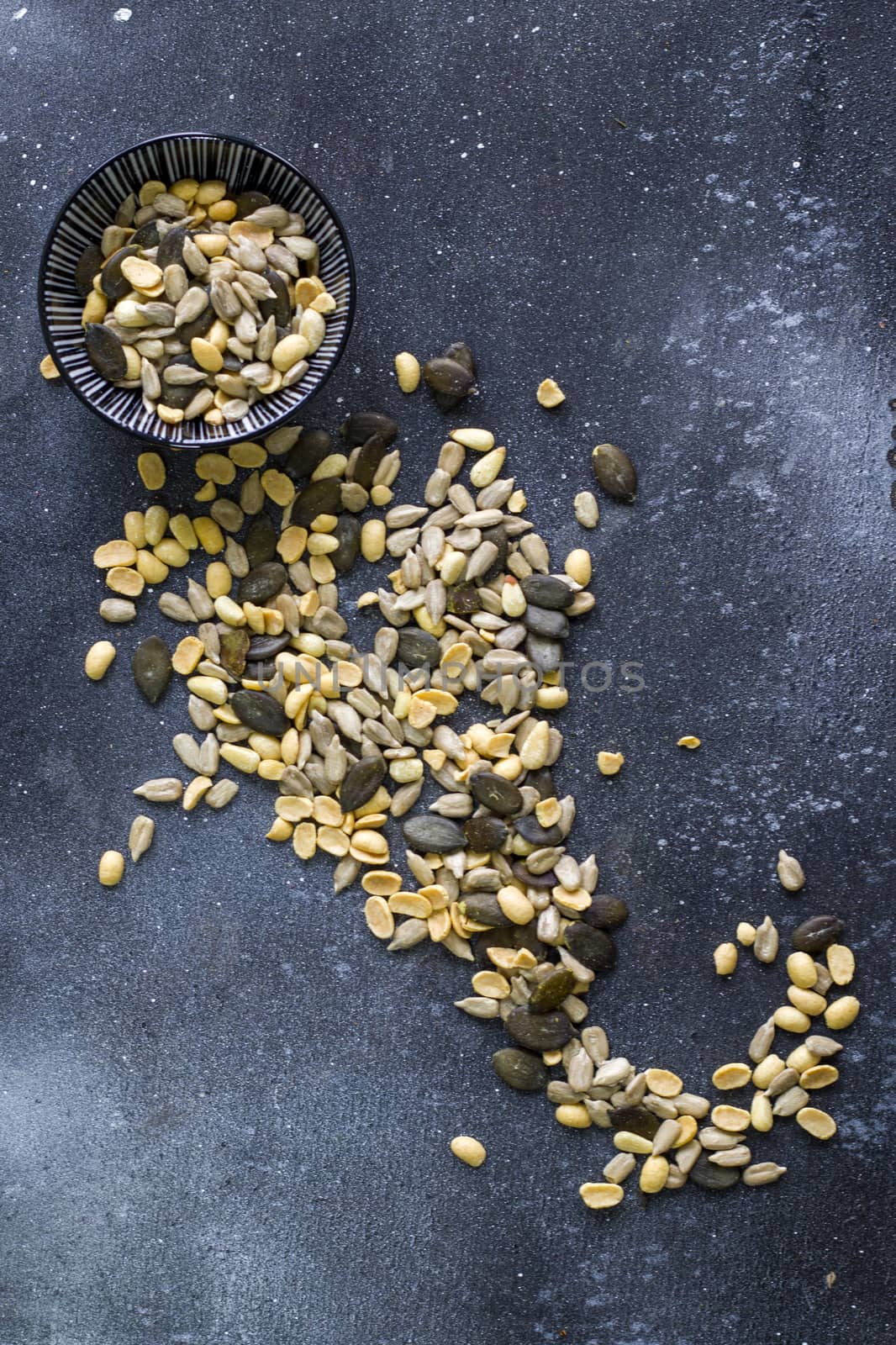 Sunflower and pumpkin seeds in bowl on the blue background. Large group of seeds. Snack and appetizer.