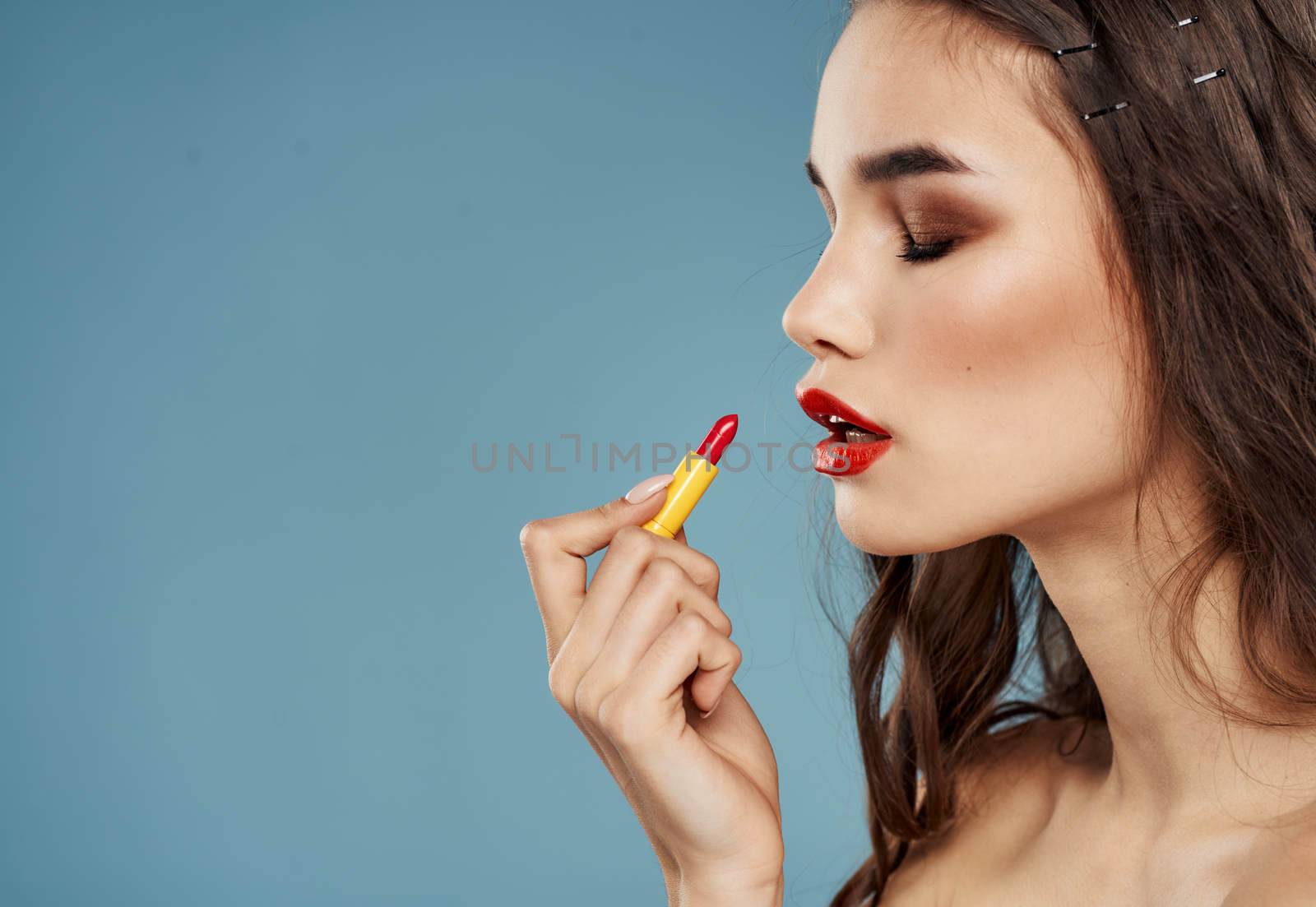 Red lipstick on blue background and brunette model female hands cropped view by SHOTPRIME