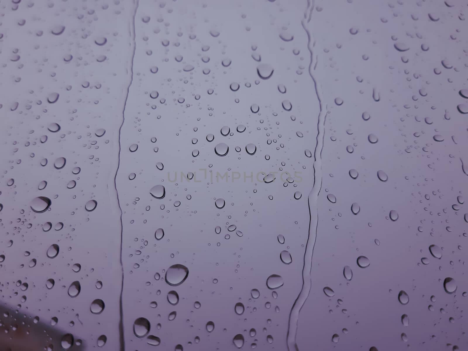 Genova, Italy - 10/22/2020: Water​ rain​ drops​ on​ glass​ background.​ Rain​ drops​ on​ a​ Windows. Hdden sunset in autumn after rain.