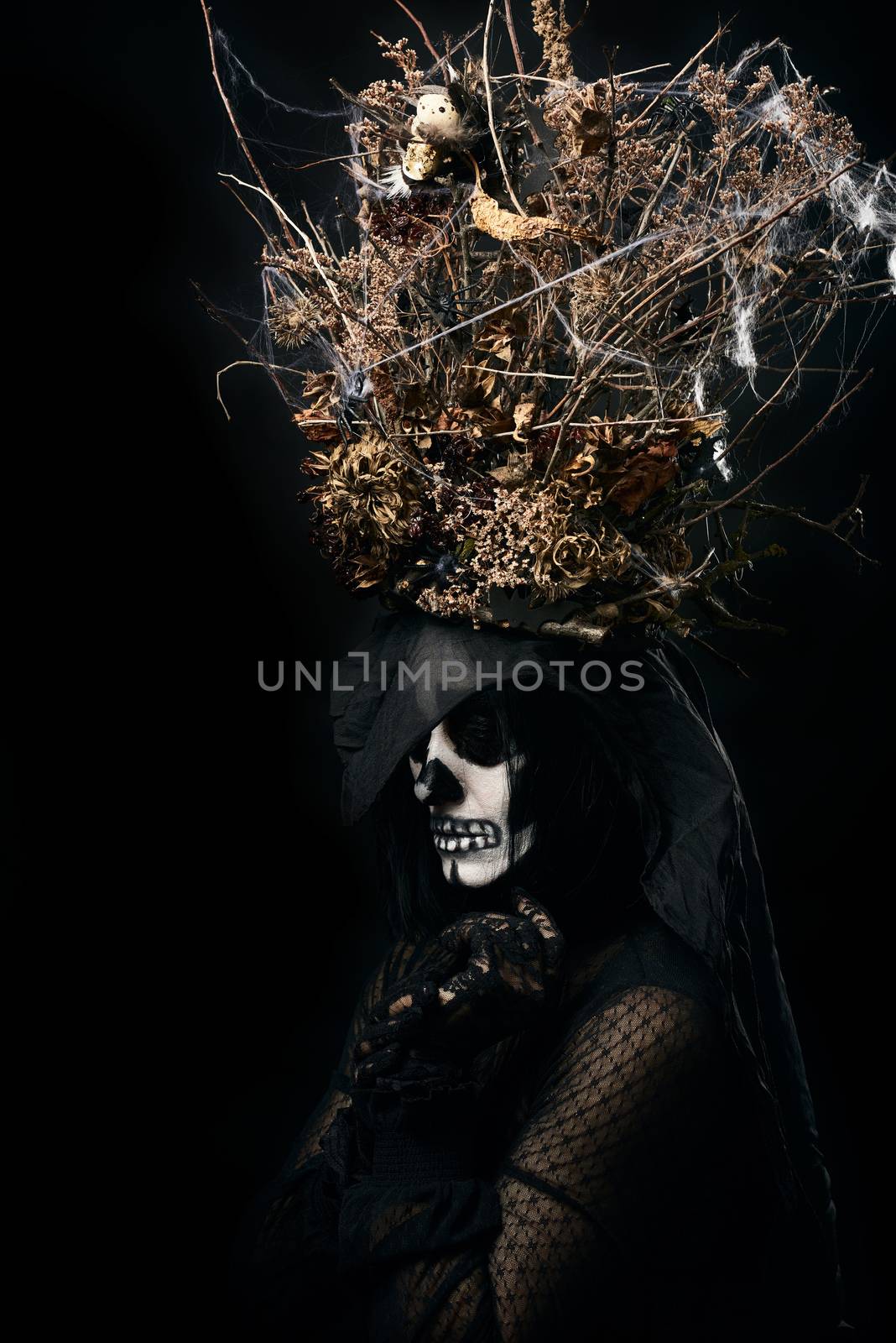 woman in black clothes and skull makeup, a crown of dry branches and flowers on her head, black background, Halloween carnival costume