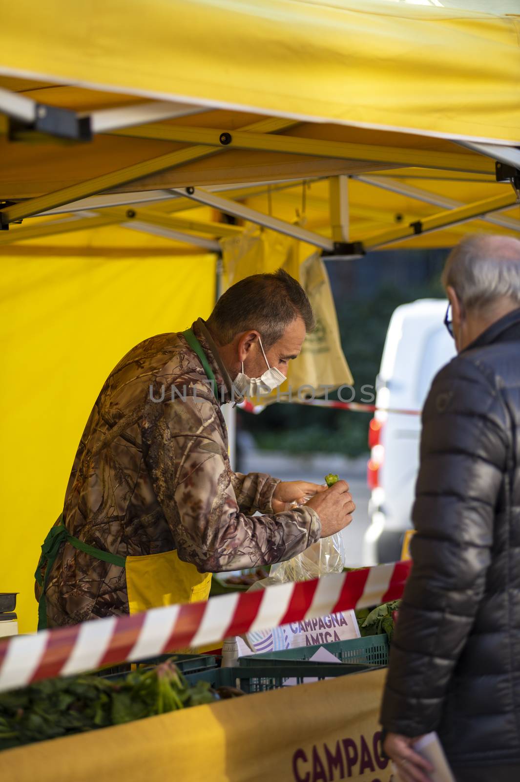 terni,italy october 23 2020:walking man with medical mask at the market selling vegetables