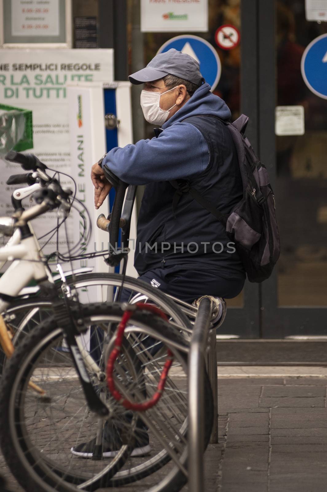 man sitting with medical mask leaning on a crutch by carfedeph