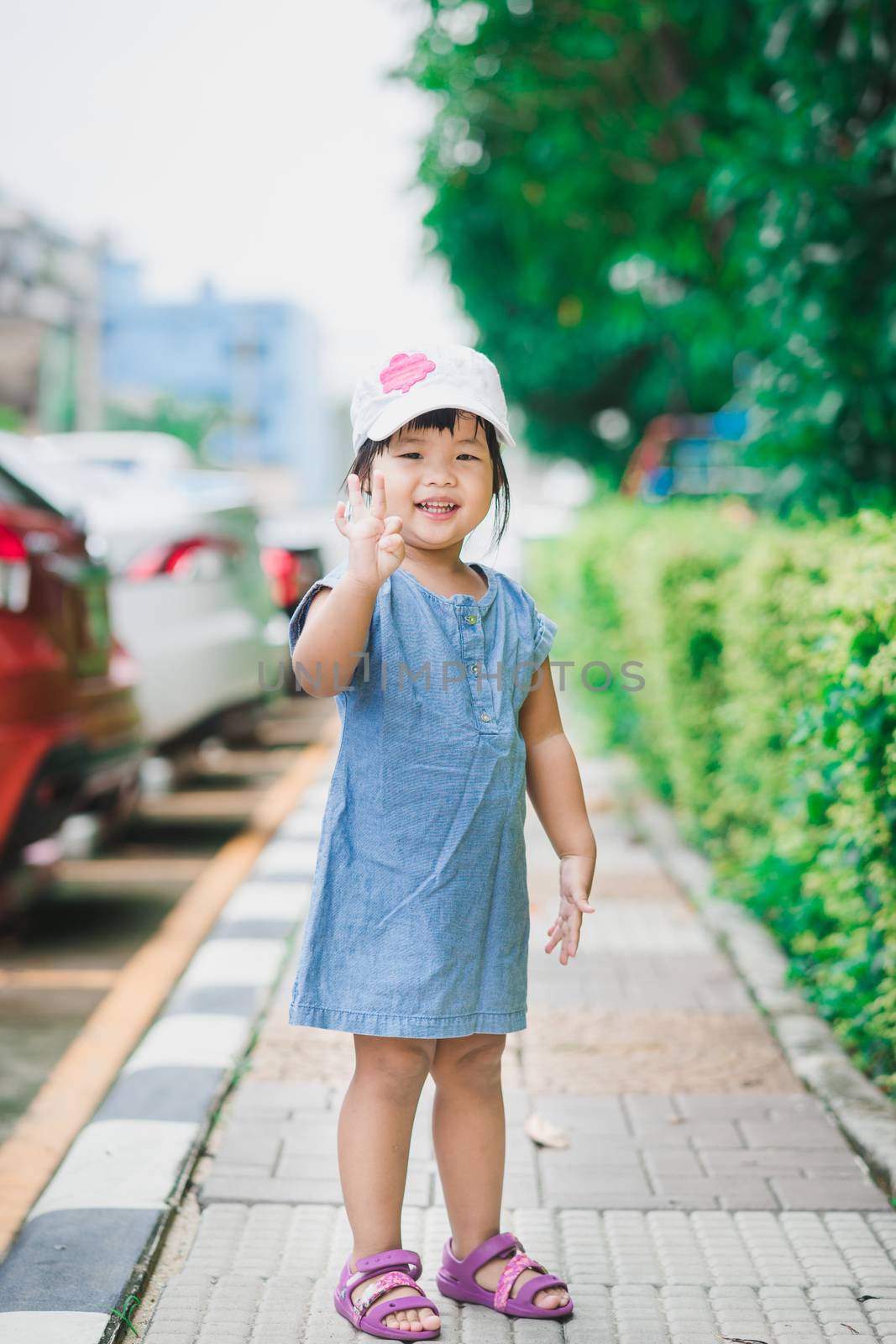little girl wear white hat standing in the park and smiling happy,ready to travel