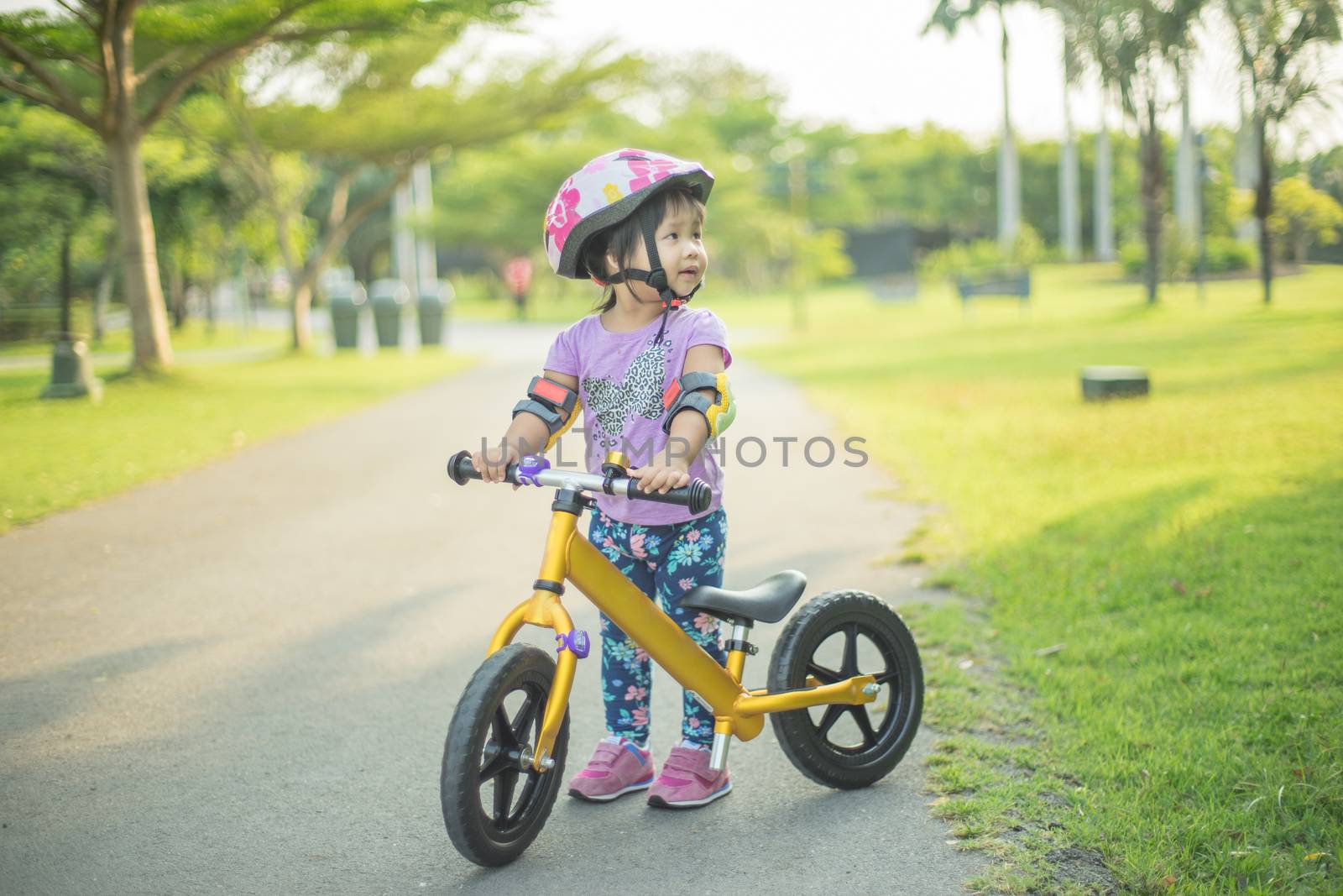Little girl learns to riding balance bike in the park