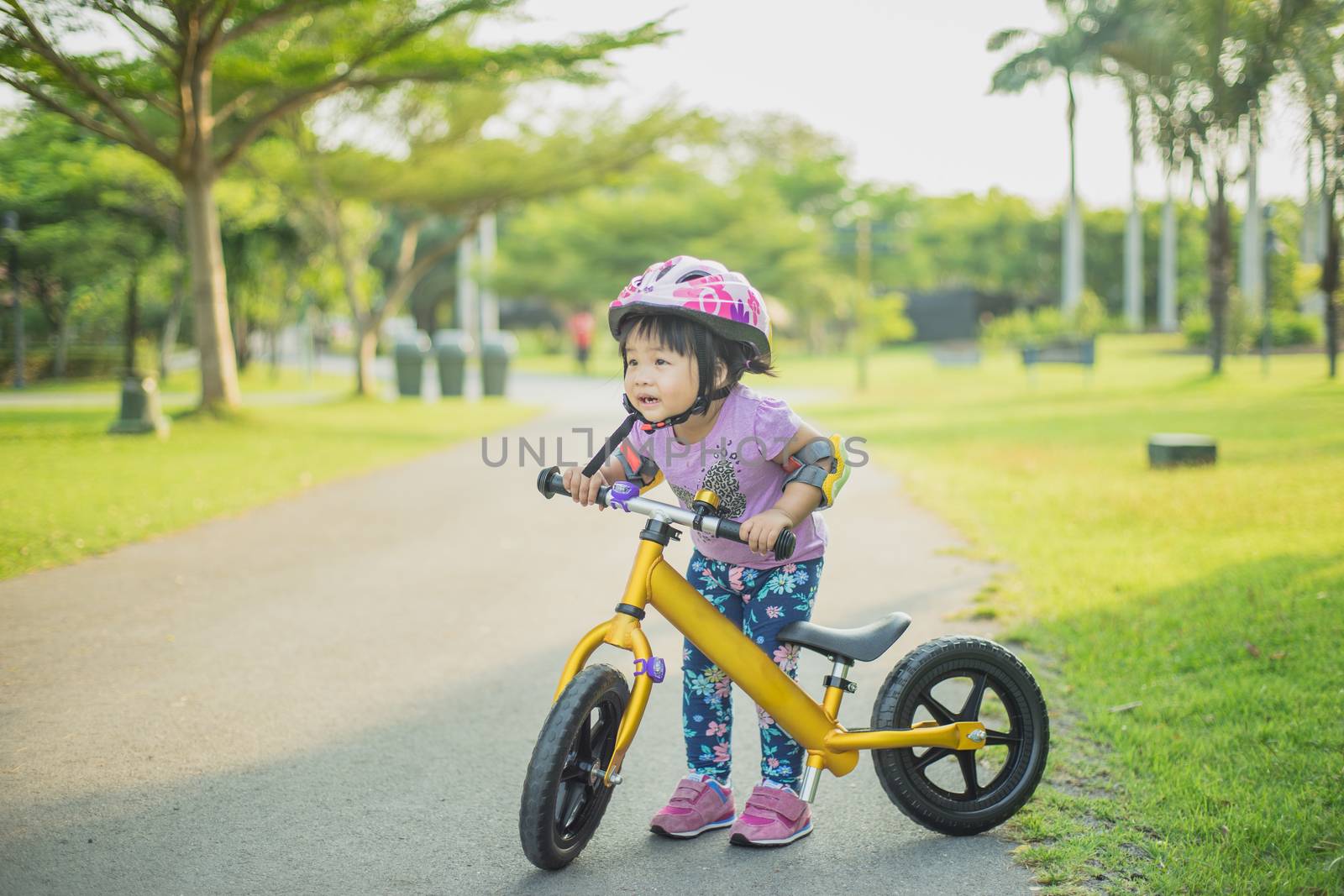Little girl learns to riding balance bike in the park