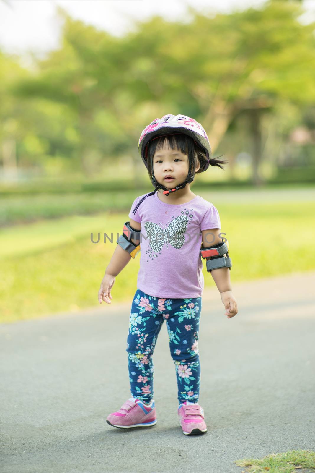 Little girl in cycling wear ready to learn riding balance bike in the park
