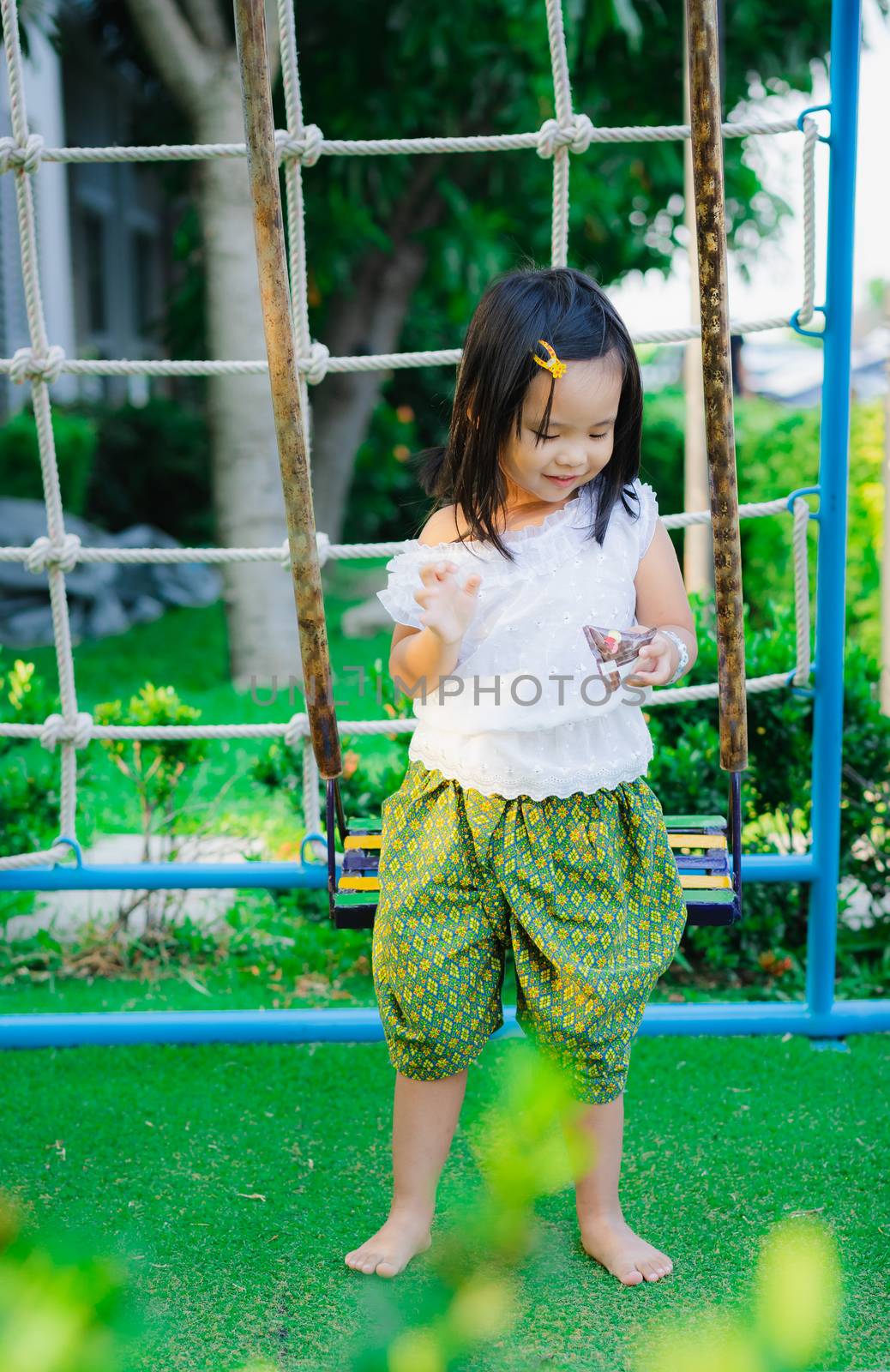 happy asian little girl in Thai period dress playing in a children playground