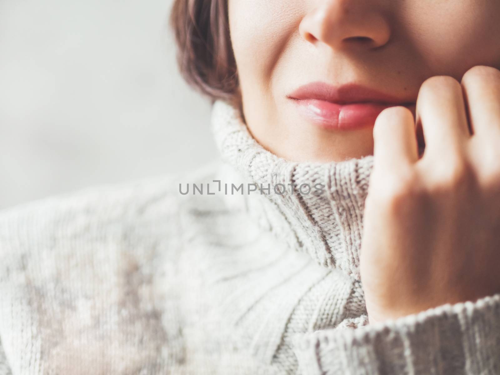 Close up portrait of woman snuggling in warm grey sweater. Casual outfit for cold weather at winter season.