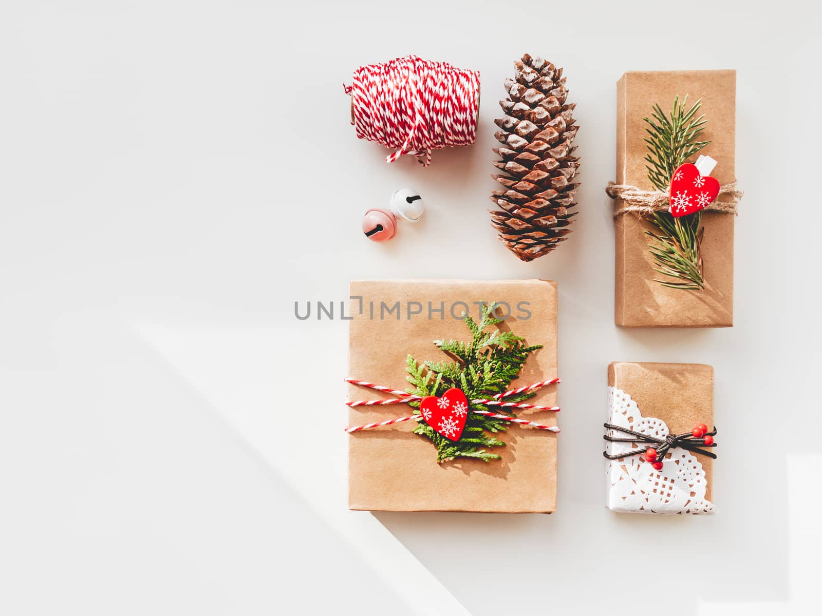 Christmas DIY presents wrapped in craft paper with fir tree twigs and red hearts. Top view on decorations on New Year gifts. Festive background. Winter holiday spirit. Banner with copy space.