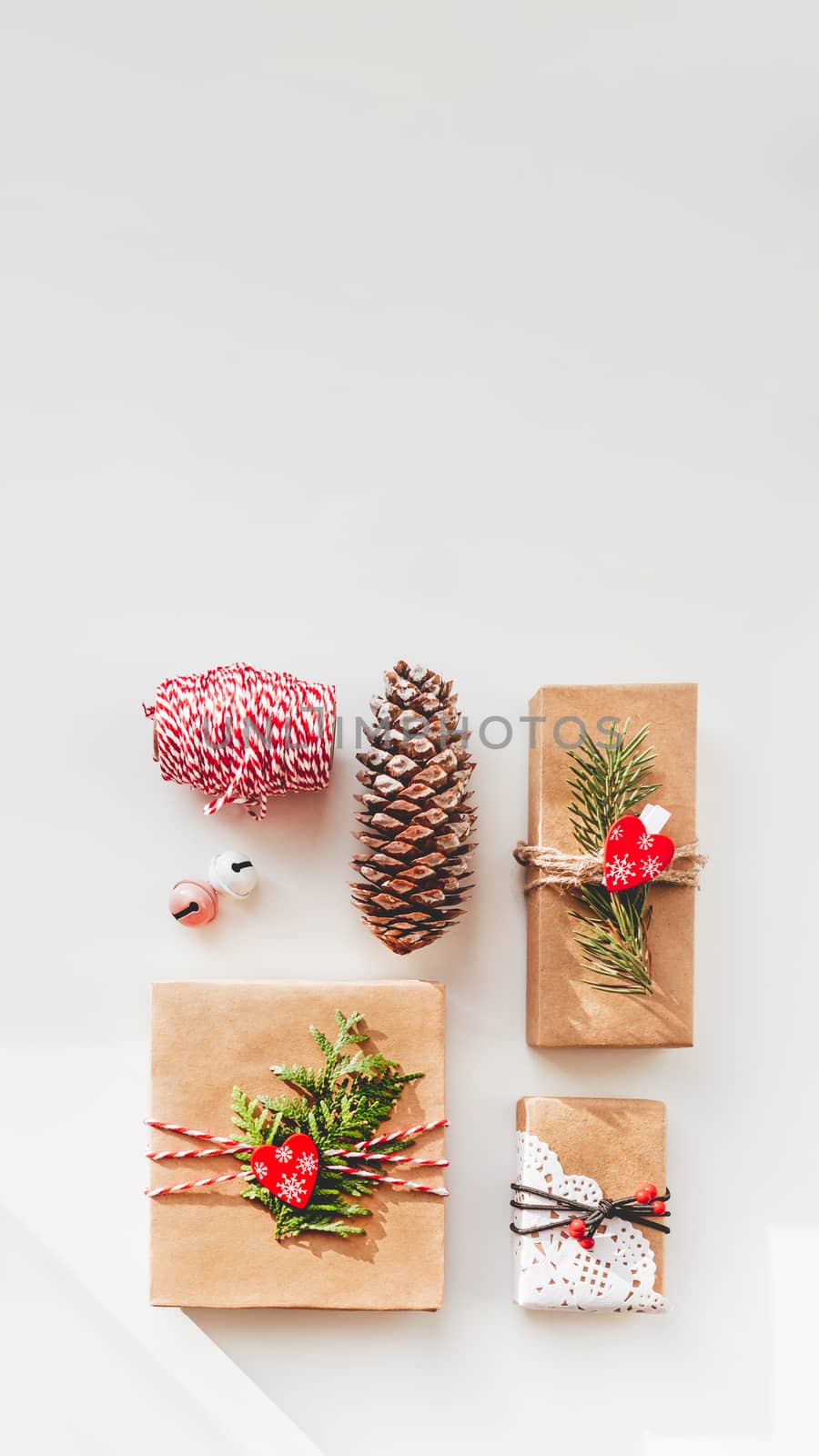 Christmas DIY presents wrapped in craft paper with fir tree twigs and red hearts. Top view on decorations on New Year gifts. Festive background. Winter holiday spirit. Banner with copy space. by aksenovko