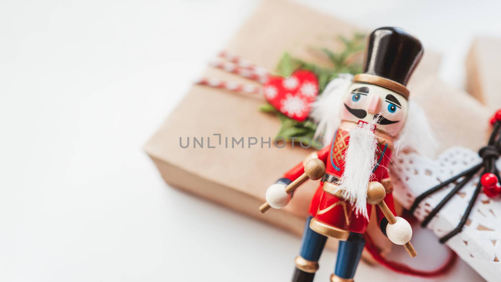 Christmas DIY presents wrapped in craft paper and wooden Nutcracker toy. Decorations on New Year gifts. Festive background. Winter holiday spirit. White background with copy space.