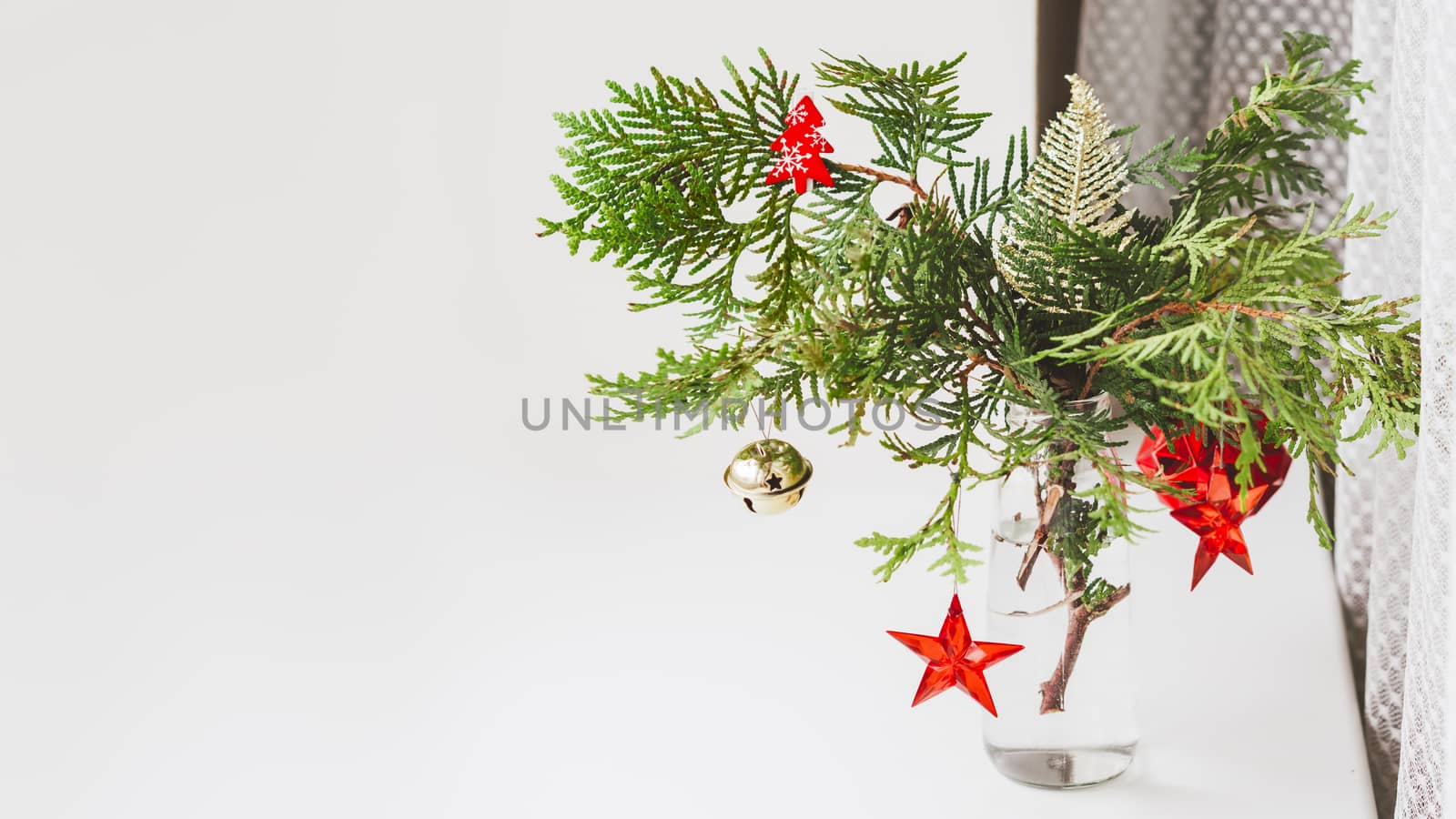 Vase with decorated thuja branches stands on window sill. Sustai by aksenovko