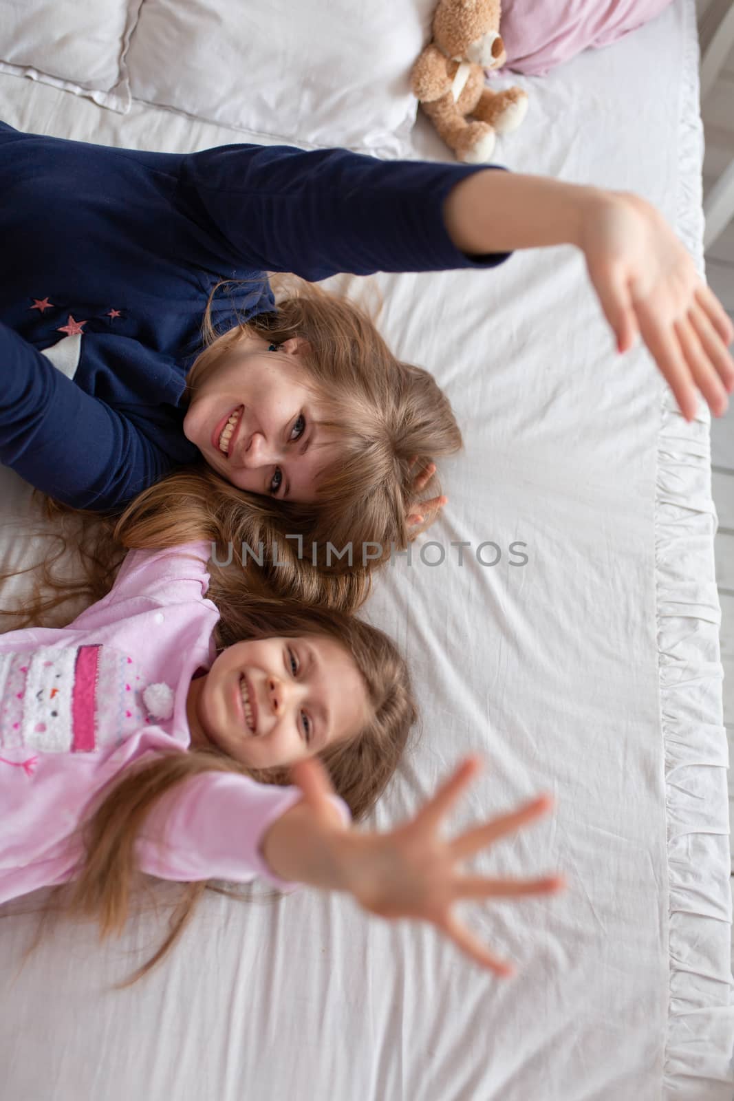Little girl spends time playing with mom while lying in bed.