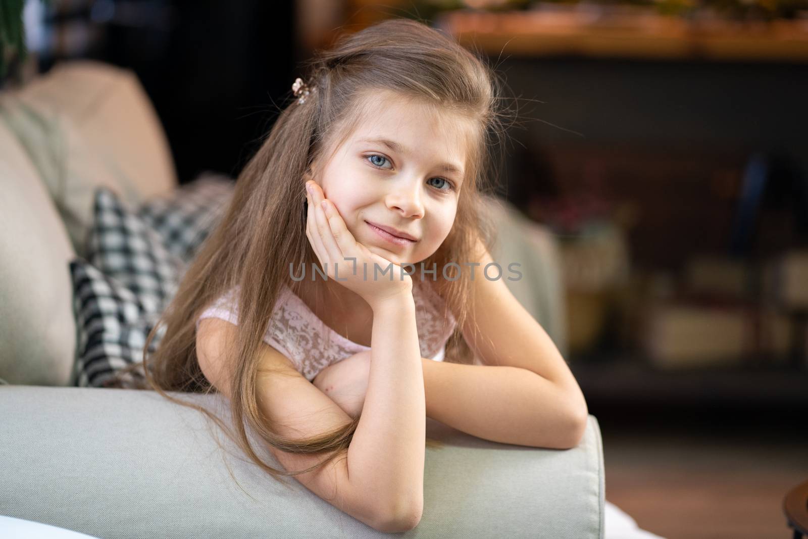 Portrait of a little girl who lies on the sofa, leaning on her arm.