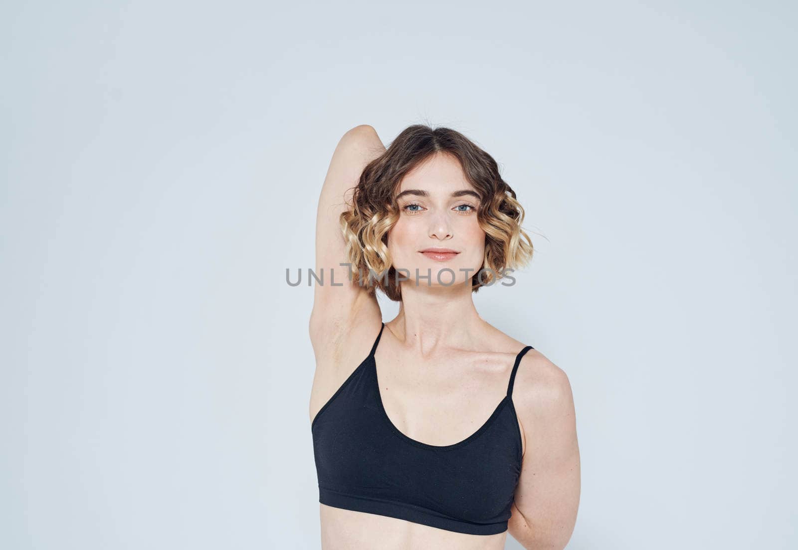 A strange woman in a short T-shirt has joined her hands behind her back on a light background. High quality photo