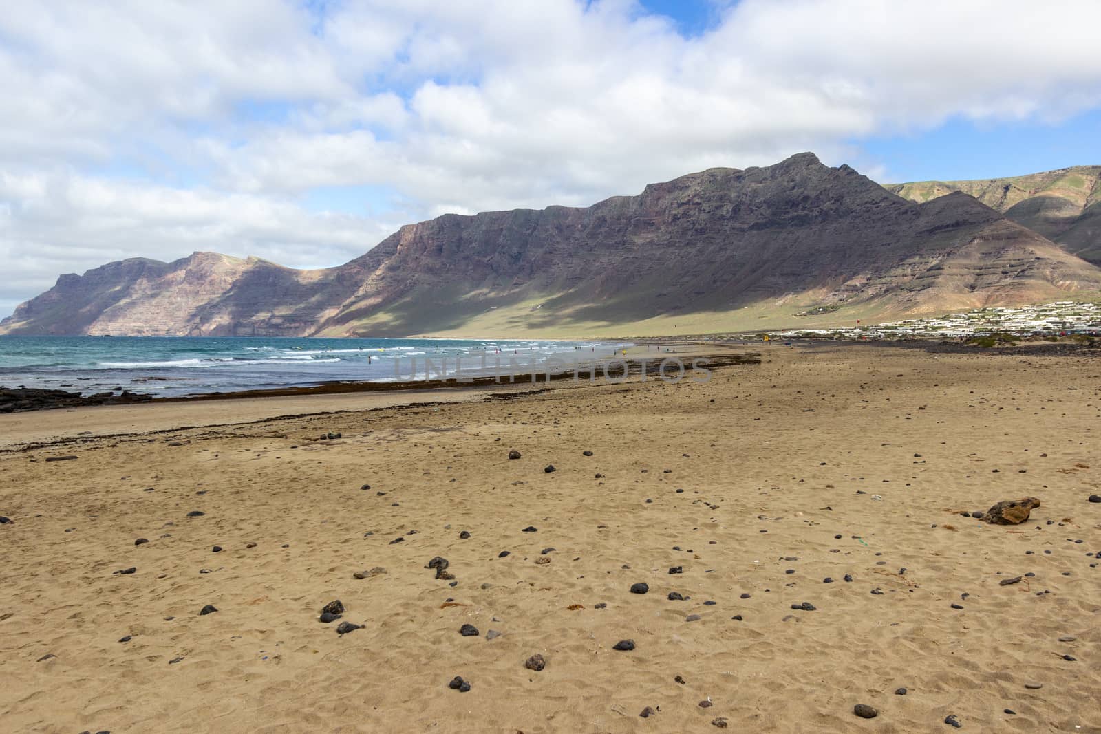 Coastline and sand beach Playa de Famara with mountain range and ocean waves on canary island Lanzarote, Spain