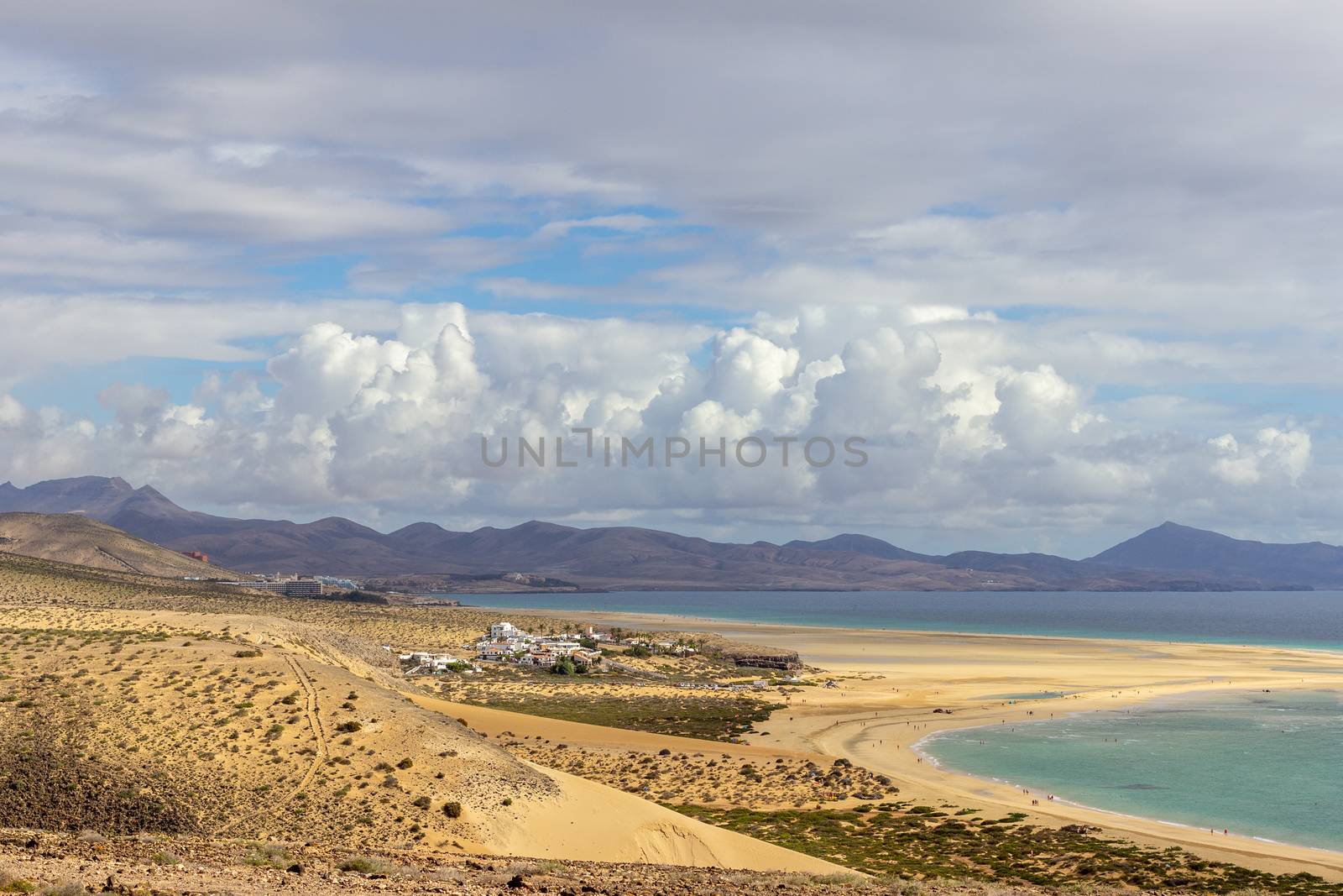 Panoramic view at sandy beach of Risco del Paso on canary island Fuerteventura, Spain  with  turquoise water and mountain range in the background