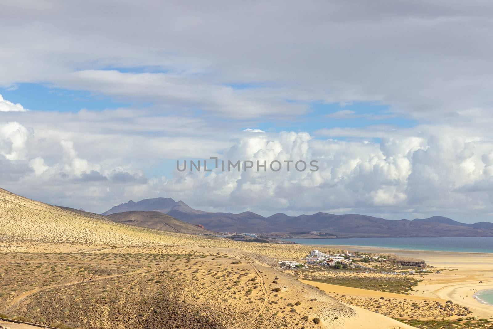 Panoramic view at sandy beach of Risco del Paso on canary island Fuerteventura, Spain  with  turquoise water and mountain range in the background